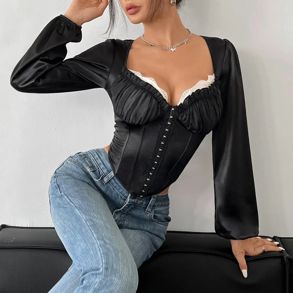 black satin long-sleeved corset top with white lace trim and front button closure featuring mesh patchwork lace chest design.
