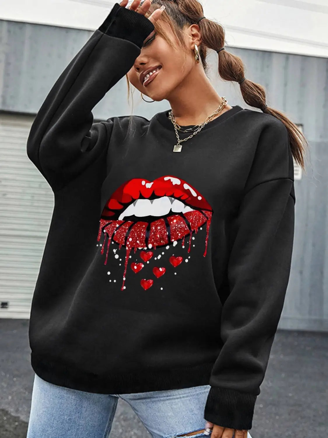 black pocketed long sleeve sweatshirt featuring bold red glittery lips graphic with dripping hearts on the front