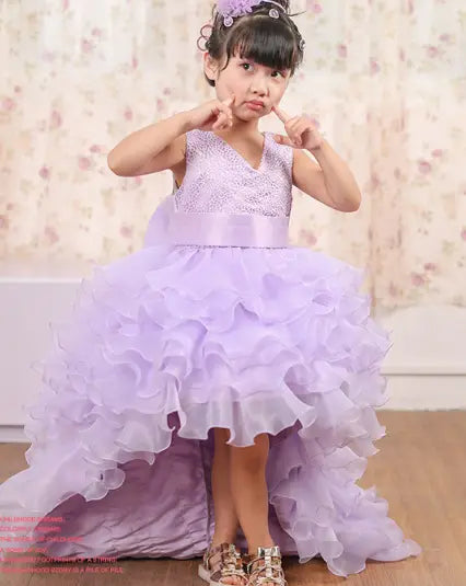 A lavender ruffled high-low dress flower girl dress with a beaded bodice and satin sash perfect for a flower girl tuxedo.