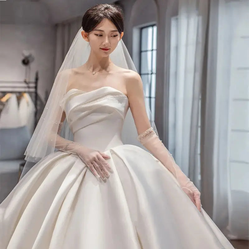 a strapless ivory satin wedding gown with a fitted bodice and voluminous skirt featuring delicate beading on the sleeves in temperament princess style french satin design