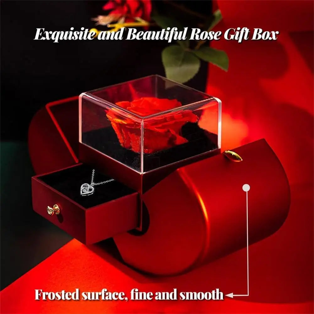 Red apple jewelry box featuring a red rose gift box with a clear acrylic top, black interior, and a silver heart pendant in the drawer.