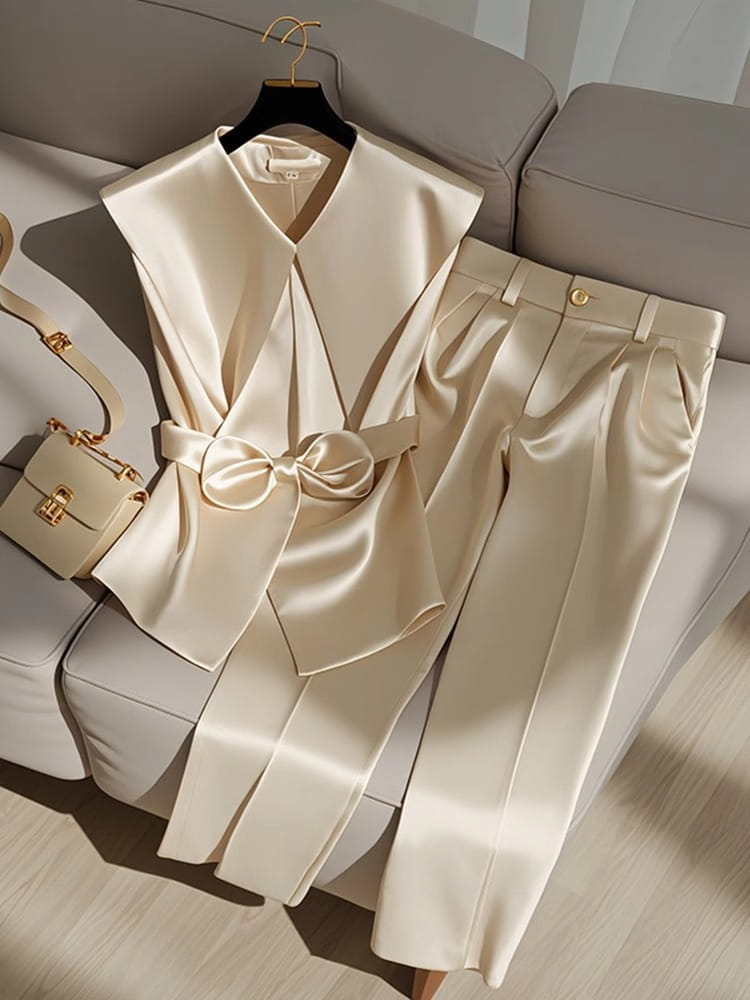Cream satin sleeveless blazer with a wide collar and matching bow belt paired with coordinating high-waisted trousers showcasing youthful fashionable champagne western style youthful attire.