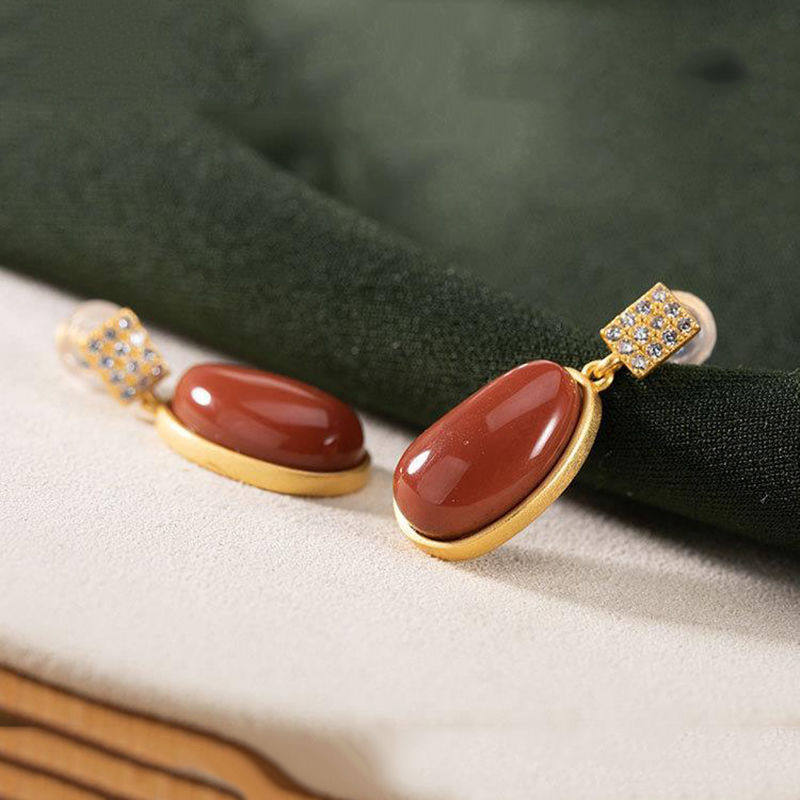 Elegant gold-toned drop earrings with oval-shaped southern red agate stones and diamond-encrusted square accents in red agate lucky bean design.