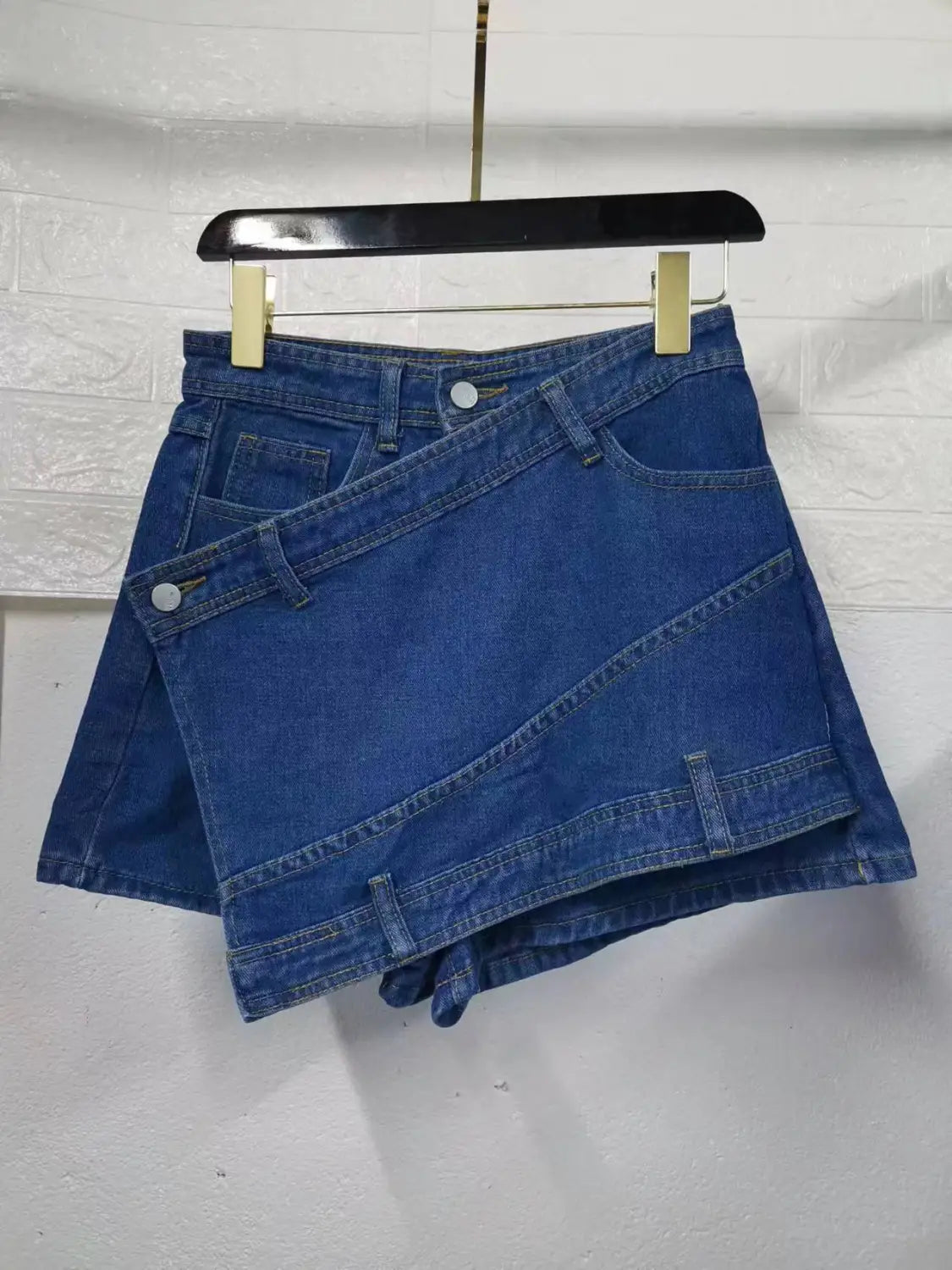 A stylish blue denim mini skirt featuring a modern asymmetrical design with overlapping panels in y2k street vintage style.