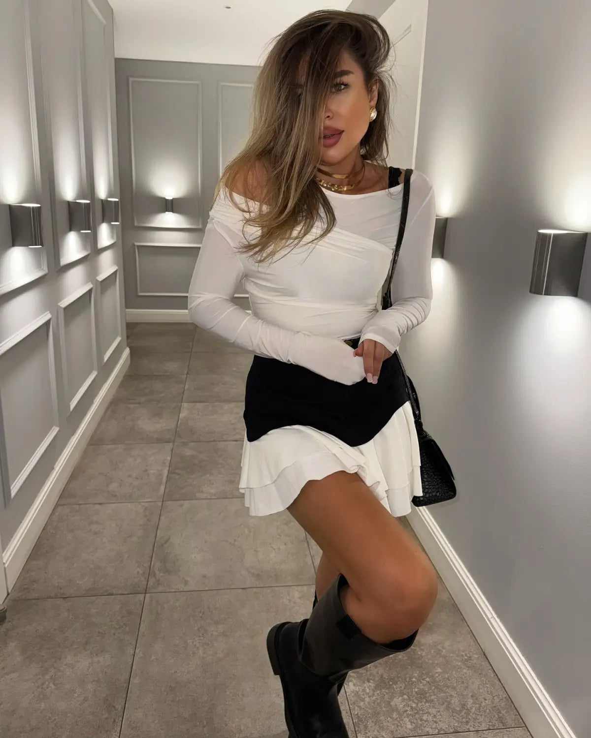 black textured shoulder bag with sleek minimalist design paired with beige two tone ruffled high waist tiered skirt highlighting the waist tiered skirt style