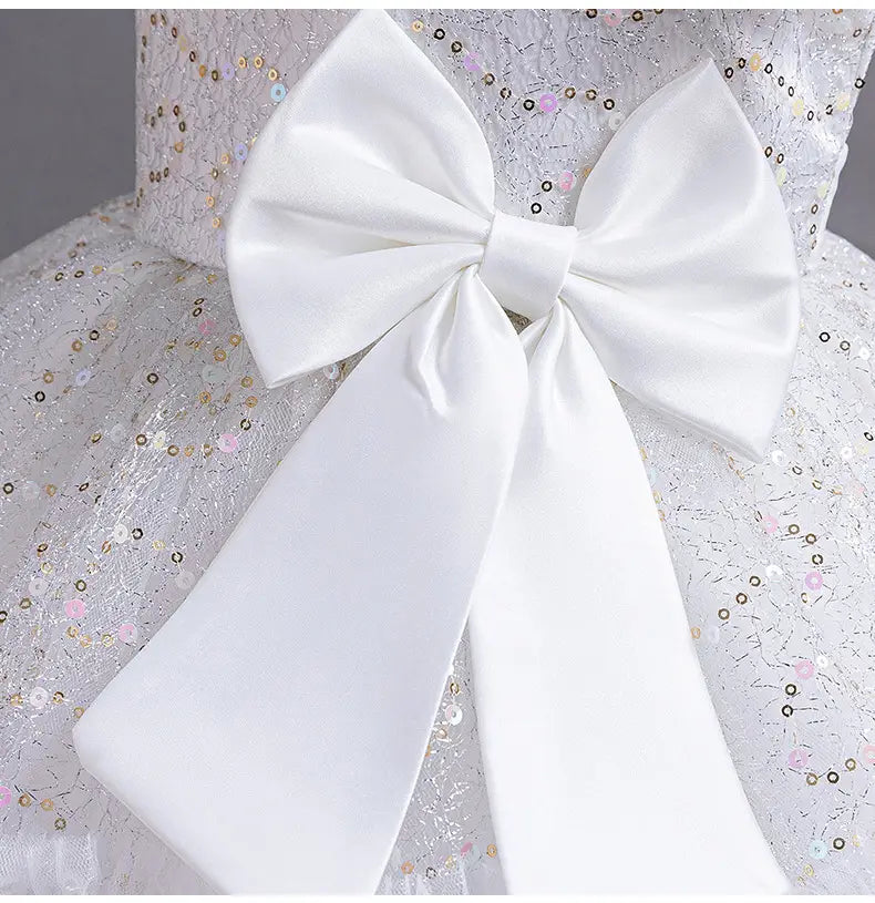 a large glossy white satin bow with long tails adorns the back of a silver sequined wedding dress tulle skirt perfect for summer occasions