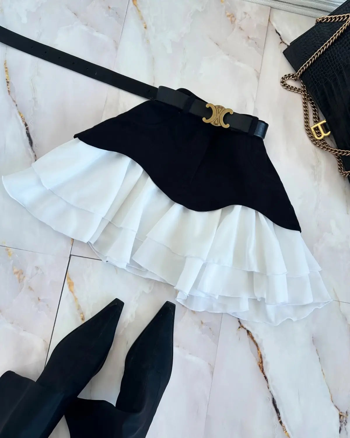 beige two tone ruffled high waist tiered skirt in black and white with a waist tiered skirt design and a black belt featuring a gold tone c shaped buckle