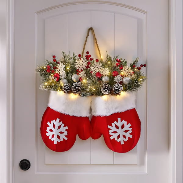 red and white christmas mittens with snowflake designs filled with festive greenery pinecones red berries and twinkling lights in a christmas garland creative glove shaped wreath.