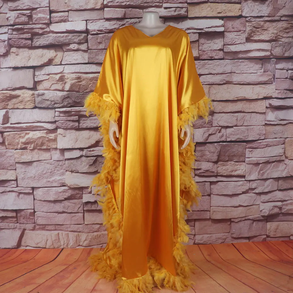 Golden satin abaya with feather trim showcasing a luxury fully surrounded loose dress luxury design in an orange feathered loose dress luxury robe.
