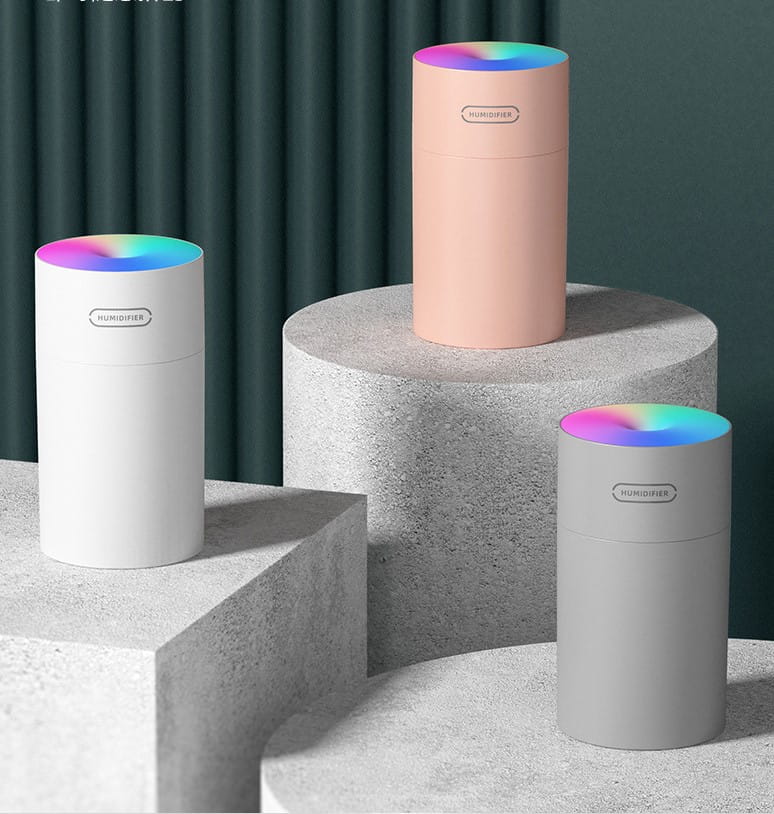 three cylindrical portable humidifiers in white, blush pink, and gray with rainbow-colored led lights on top are shown as the second generation colorful cup humidifier usb model.