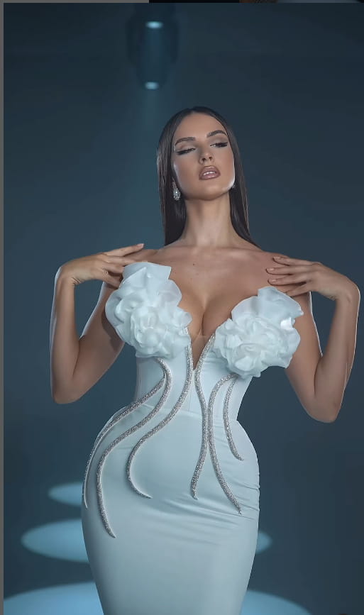 a white temperament socialite flower chain evening dress featuring a form-fitting gown with large floral embellishments at the shoulders and silver beaded detailing along its sides