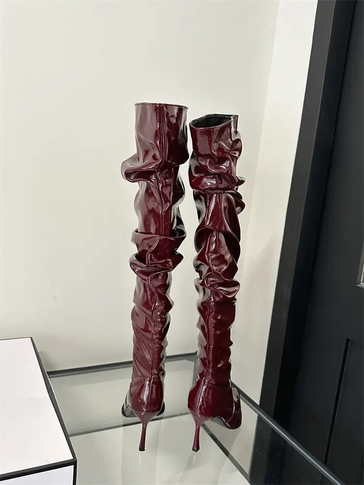 Burgundy patent leather over-the-knee boots with ruched detailing and slender autumn stiletto heel pile style.