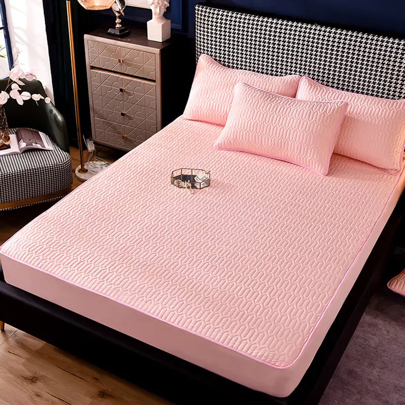 pink quilted bed sheet with a subtle wavy pattern and matching pillows showcasing a thickened all-inclusive dust-proof fitted sheet.