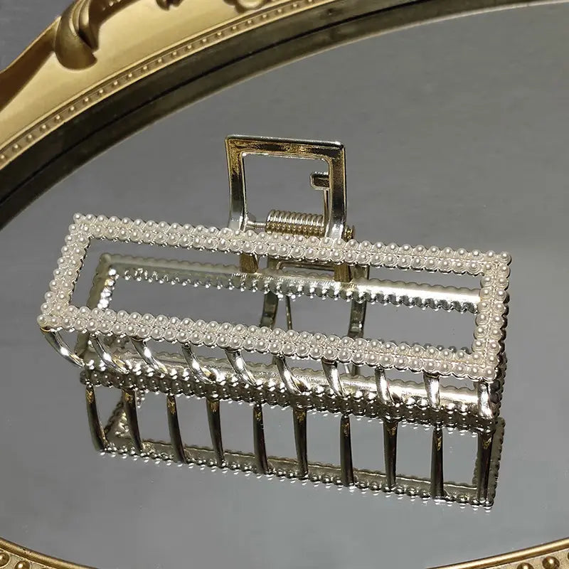Elegant sweet pearl silver claw clip features a rectangular silver frame adorned with a row of tiny sparkling pearls for a refined and stylish look.