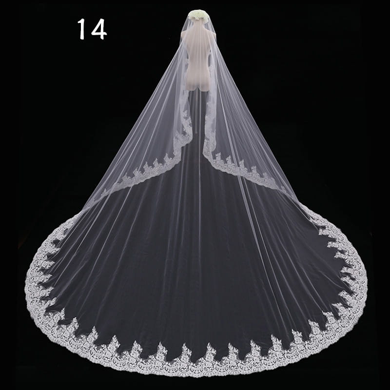 A long lace wedding veil meters wide style in white with intricate floral embroidery along its flowing lace edges.