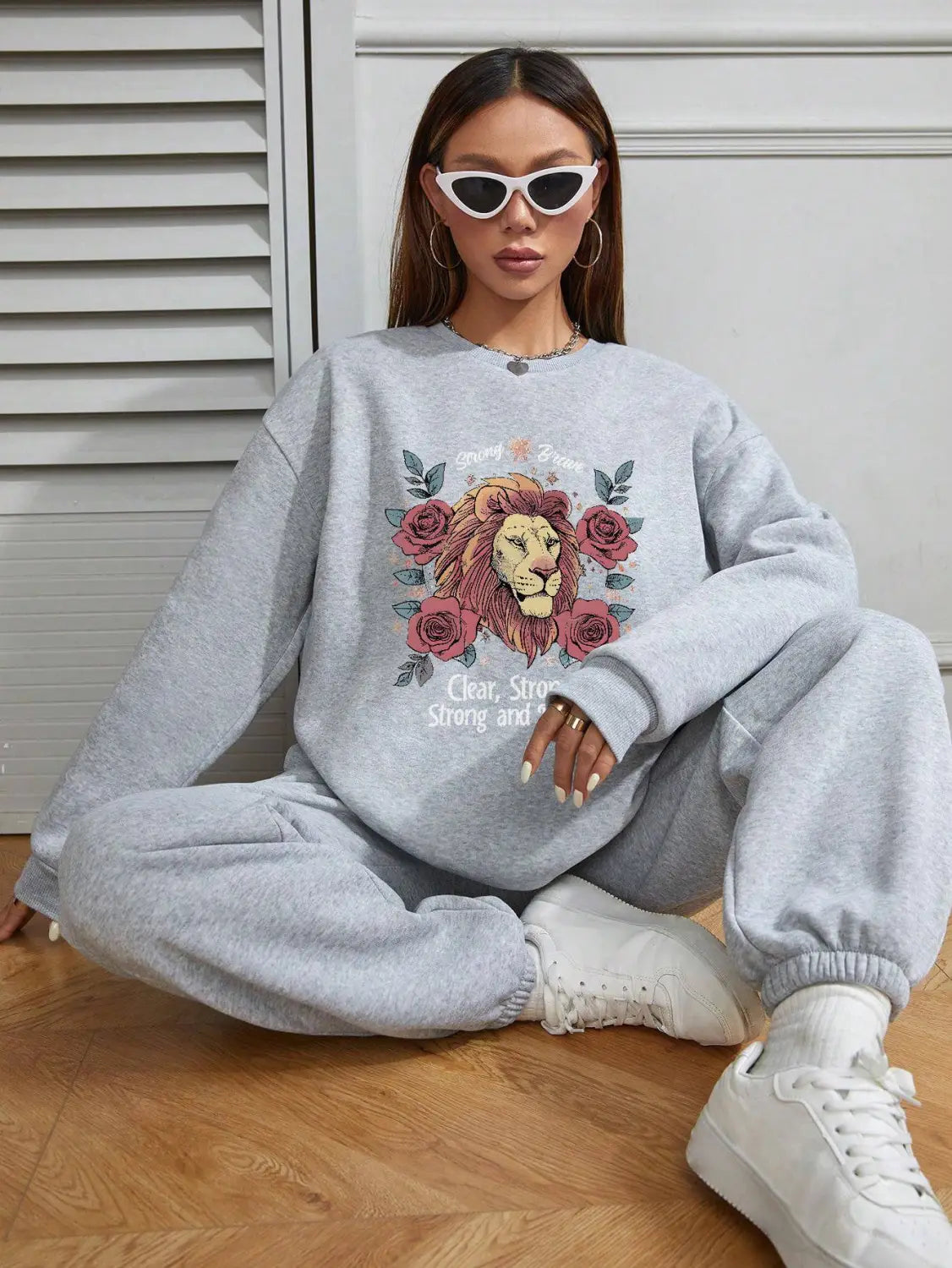 Gray lion-themed sweatshirt with rose embroidery and clear strong text in a regular fit long sleeve design.