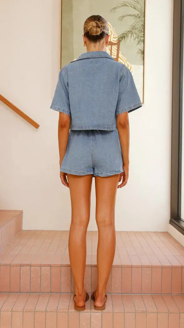 women’s irregular denim short pantskirt suit featuring light-wash denim shorts with a cropped, short sleeve loose design and button-up collar.