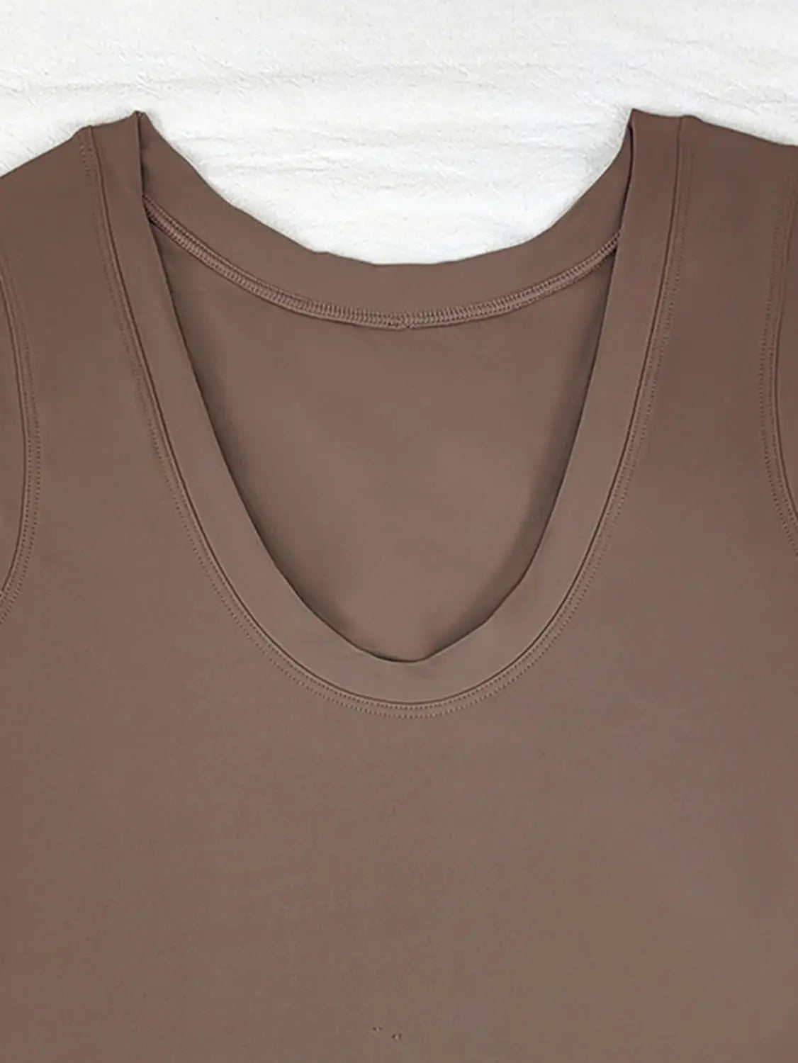 A sleek solid brown sleeveless top with smooth stretchy fabric and a softly curved neckline paired with a sleeveless side slit yoga tennis skirt sport dress.