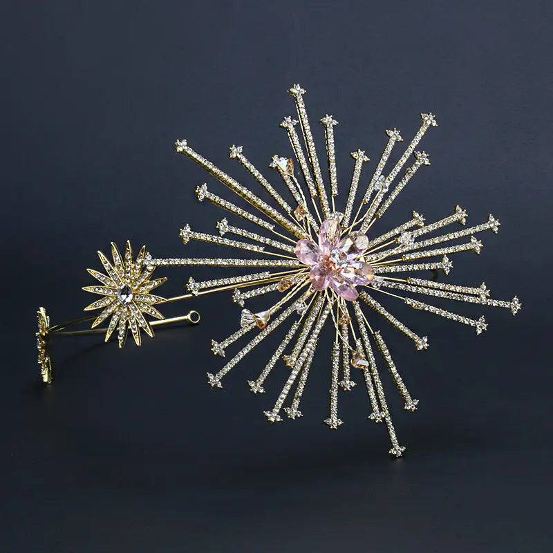 A sparkling gold starburst brooch with clear and pink crystals and a central floral design on a silver starburst bridal rhinestone headband hair accessory.