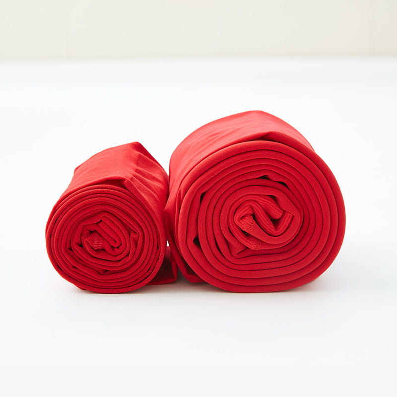 Two neatly rolled red stepping pants made from smooth and slightly stretchy outer nylon single layer fabric.