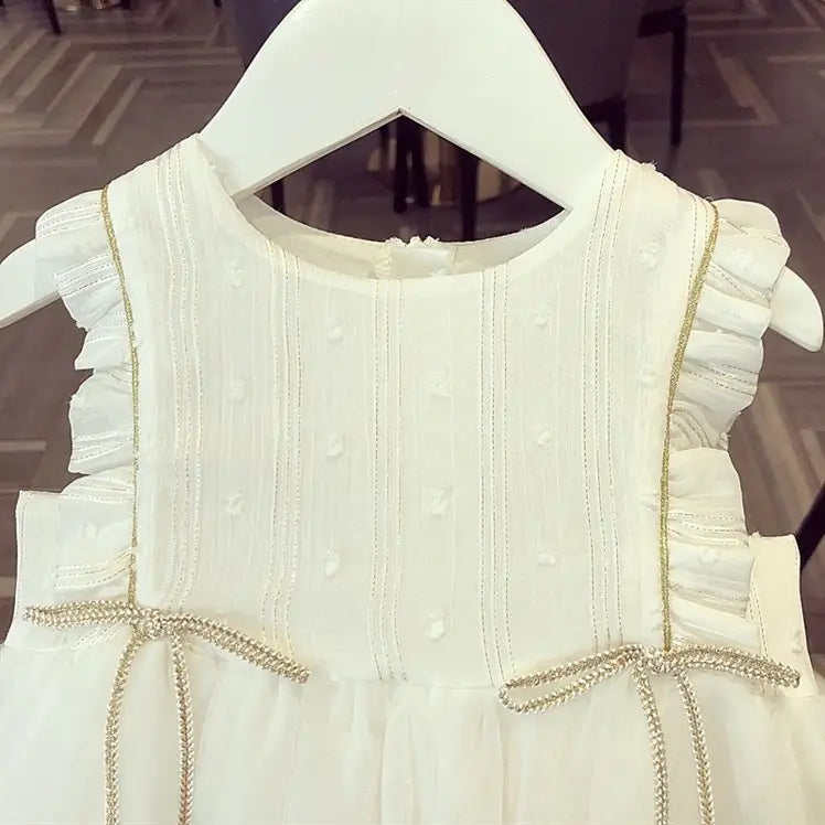 White beaded star baby gauze princess dress featuring delicate white fabric with ruffled shoulder straps, subtle vertical stitching, and decorative gold-trimmed bows perfect for summer.