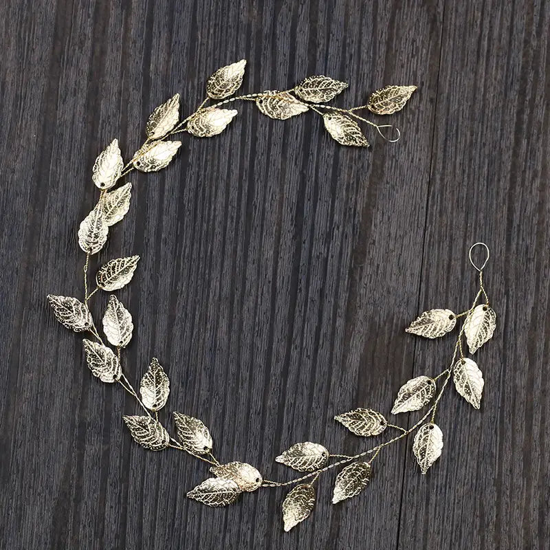 Delicate gold-toned metal leaf hair band with intricate lace-like detailing and a curved design for elegant silver leaf hair styling.