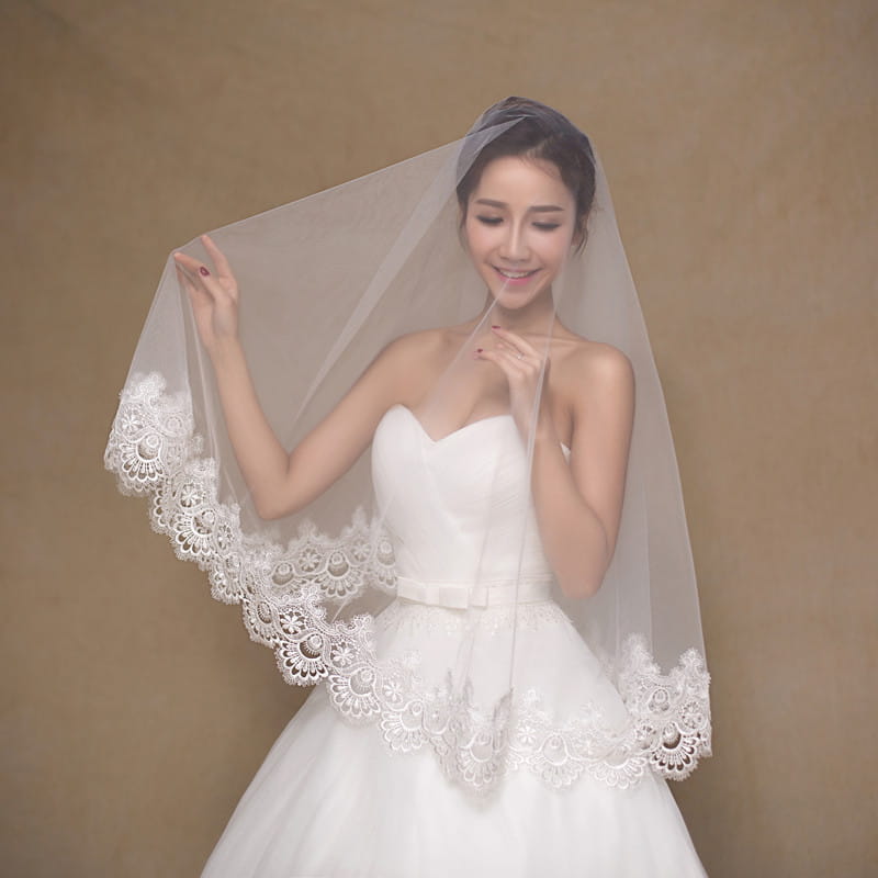 A delicate white lace floral wholesale white bride veil featuring intricate floral patterns along its edges suitable as a bride veil cheap option.