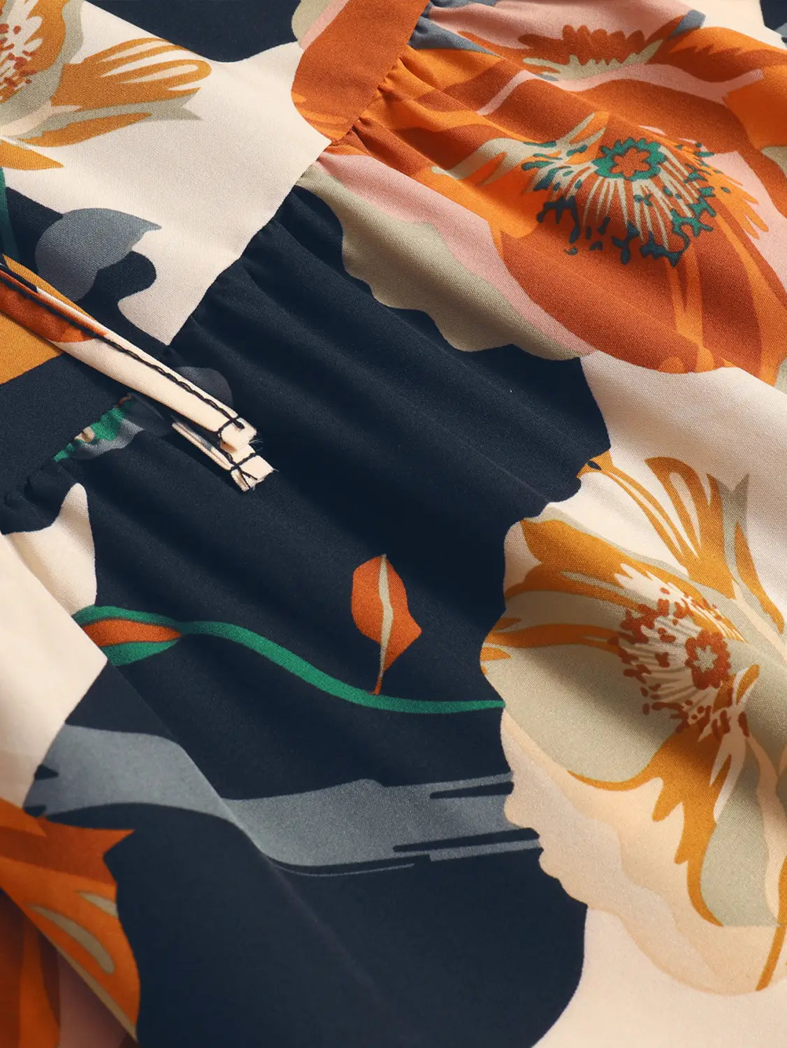 a cream tiered pleated floral print elastic waist skirt in navy blue and white with a bold oversized floral print in orange teal and cream