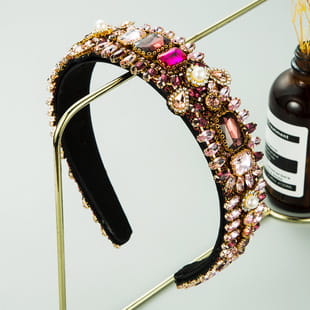 A baroque colorful headband featuring sparkling pink and gold gemstones with a velvet-lined interior.