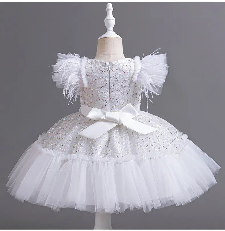 White sequined toddler wedding dress tulle with feathered short sleeves, a layered tulle skirt summer style, and a large white satin bow at the waist.