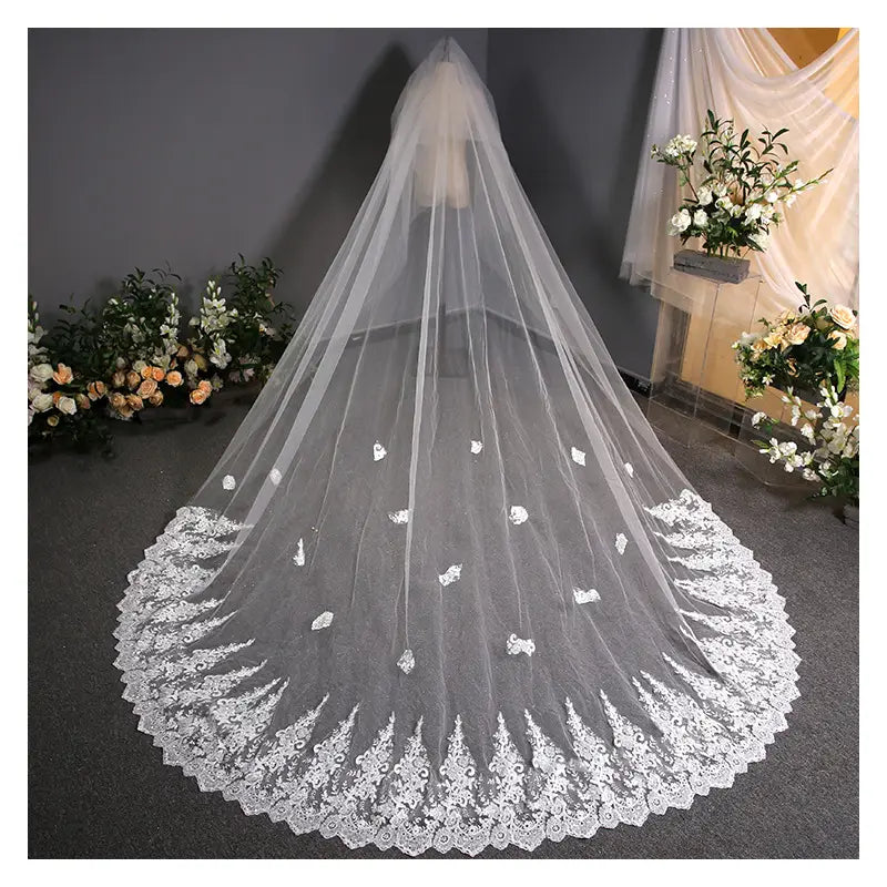 A delicate white lace wedding dress trailing veil with intricate floral embroidery and scalloped edge.