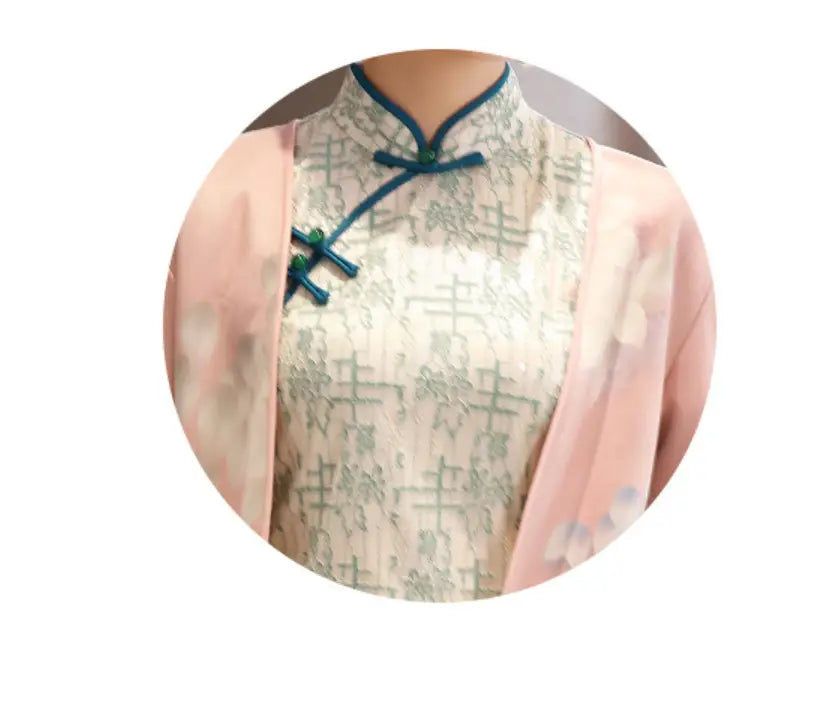 a delicate cream-colored medium length cheongsam with a subtle green pattern and teal frog closures paired with a matching jacket in the floral dress set