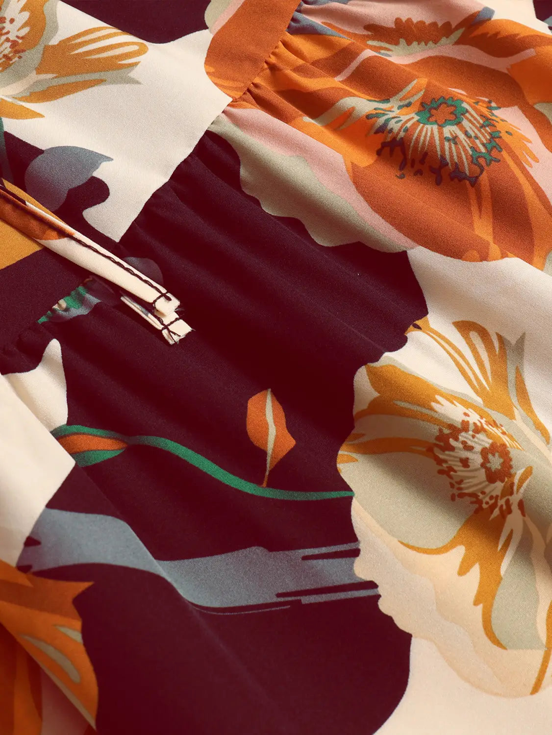 a cream tiered pleated floral print elastic waist skirt featuring a flowing dress design with bold floral print in shades of orange maroon and cream