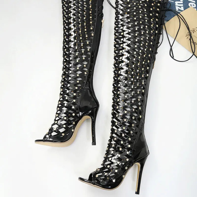 Black studded lace up high heel sandal boots featuring black patent leather over-the-knee design with geometric lattice and silver studs.