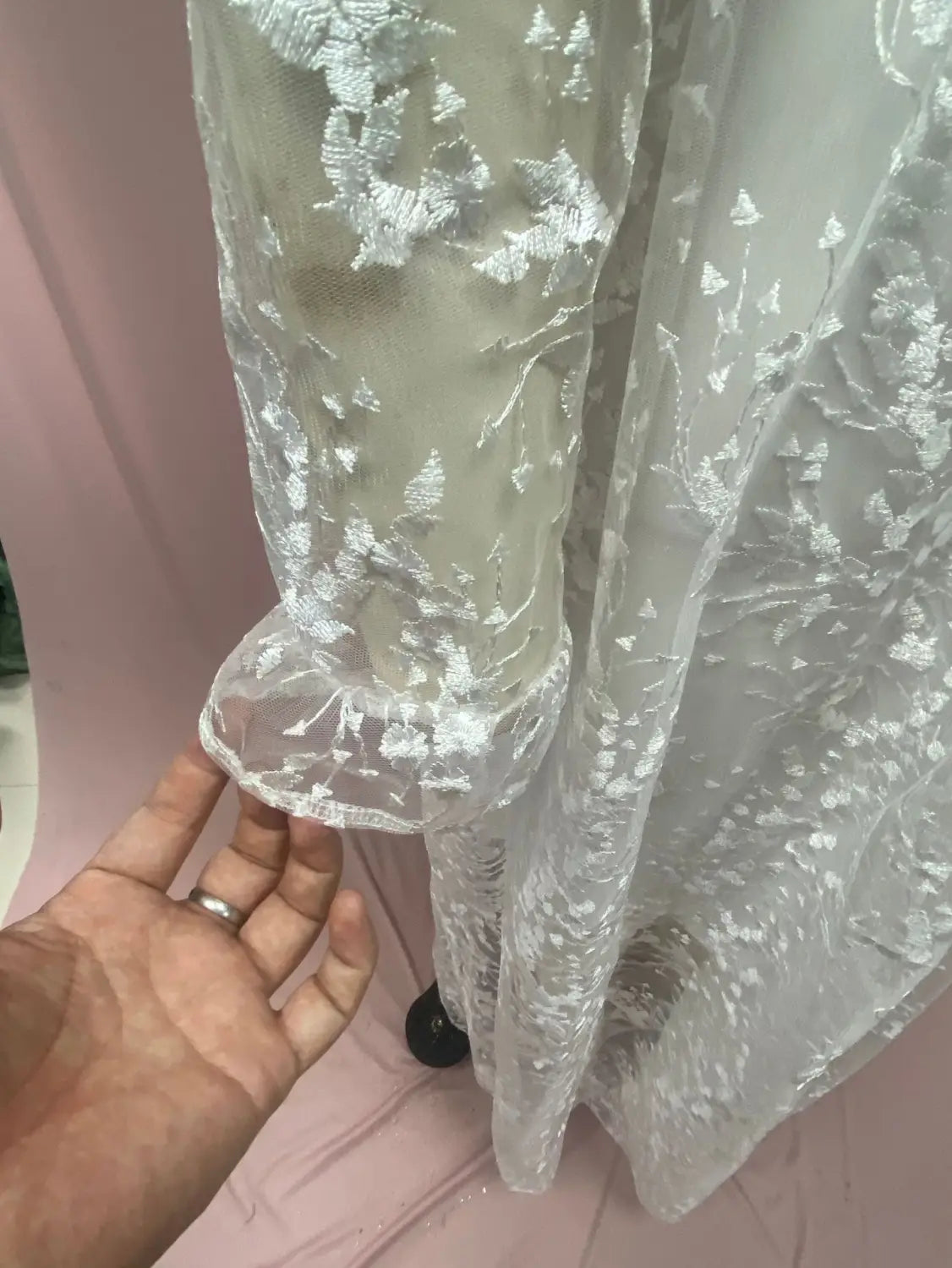 A delicate sheer white long sleeve wedding dress lace gown featuring intricate silver embroidery and flared sleeve cuffs.