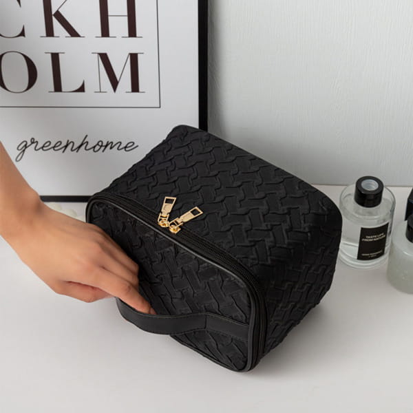 Black premium large capacity cosmetic bag made of woven-textured material with gold-tone zipper pulls and a matching handle.