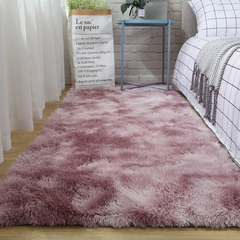 A plush carpet floor featuring a gradient-pink shaggy area rug with soft fluffy texture and subtle color variation from deep rose to lighter blush designed as a carpet floor mat.