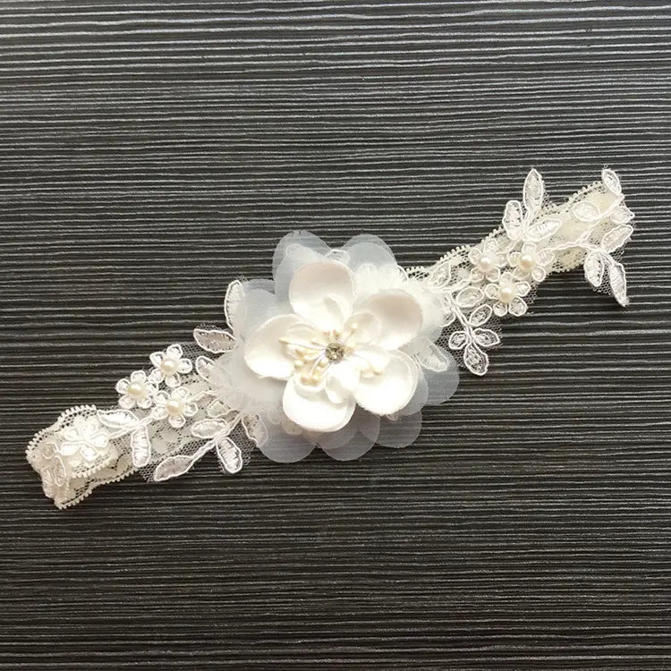 a delicate white lace bridal garter featuring a central floral appliqué and small pearl accents designed as a wedding supplies elastic leg ring