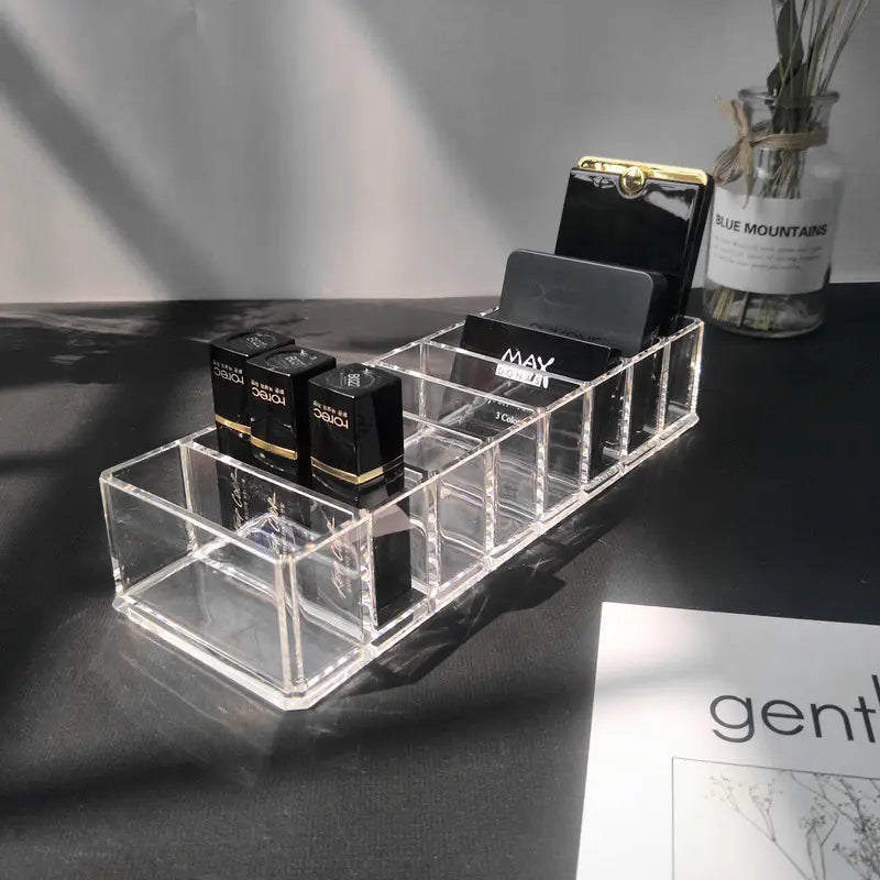 Clear acrylic makeup organizer with multiple compartments holding black lipstick tubes and card slots in a makeup organizer image.