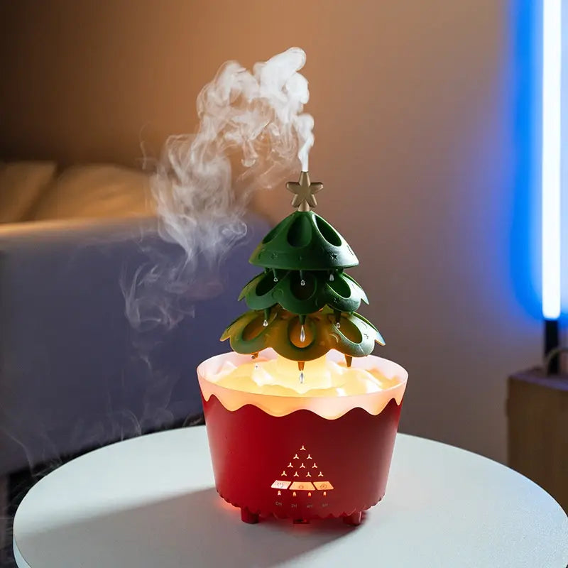Red ceramic Christmas tree essential oil aroma diffuser with green plastic tiers and gold star topper emitting mist from its top for design essential oil and oil aroma diffuser use.