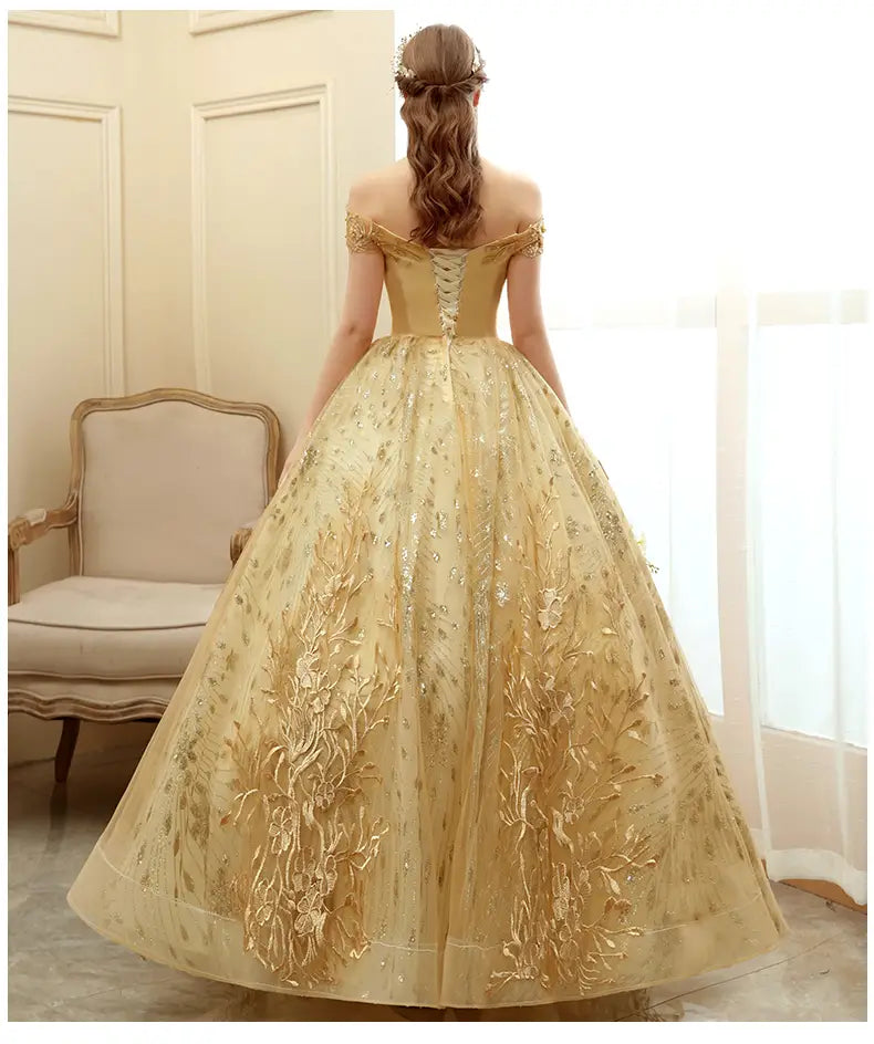 A shimmering gold off-the-shoulder solo performance costume tutu featuring intricate floral embroidery and a voluminous tulle skirt.