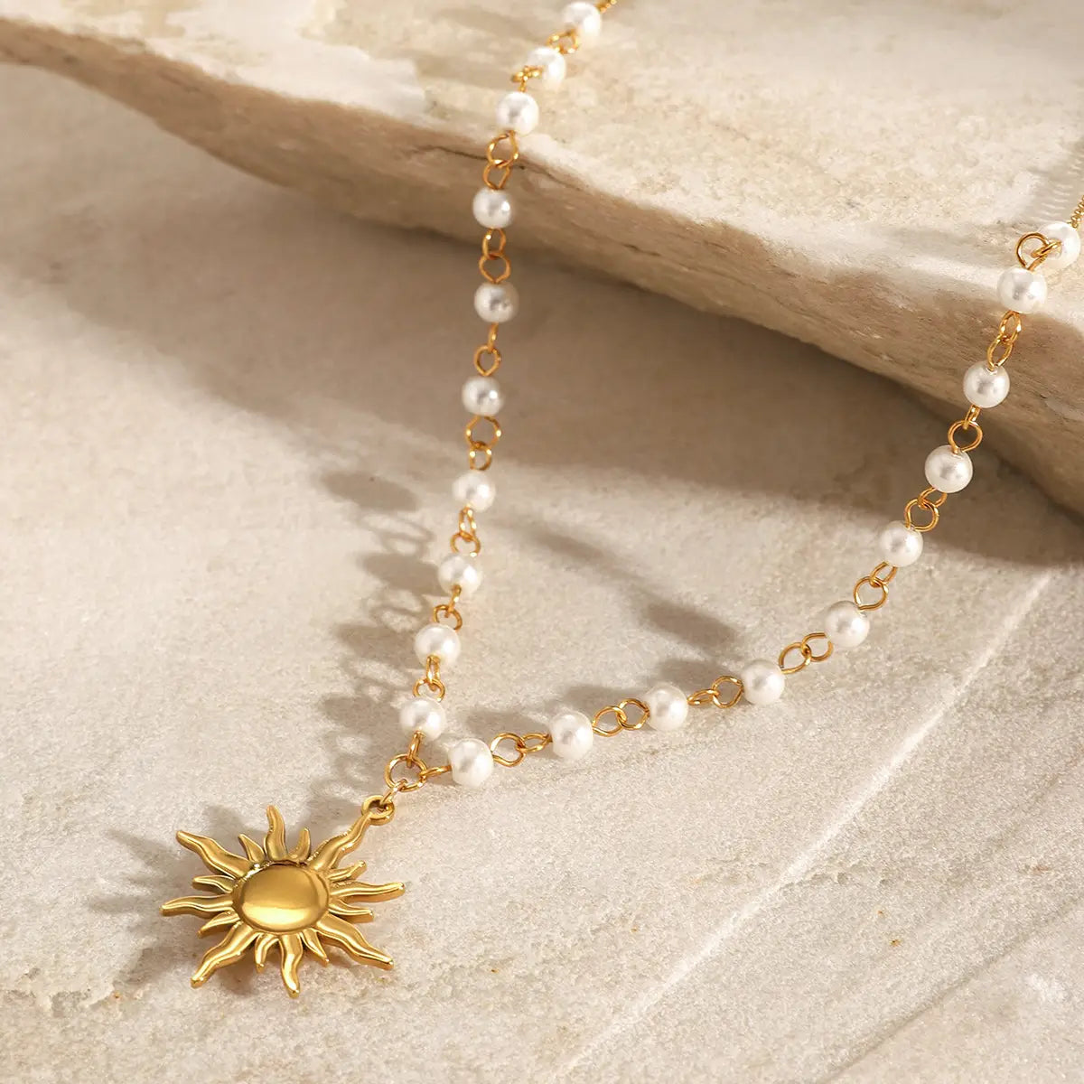 a delicate gold sun pendant necklace with a string of small white pearls made of stainless steel pearl material in a steel pearl necklace design