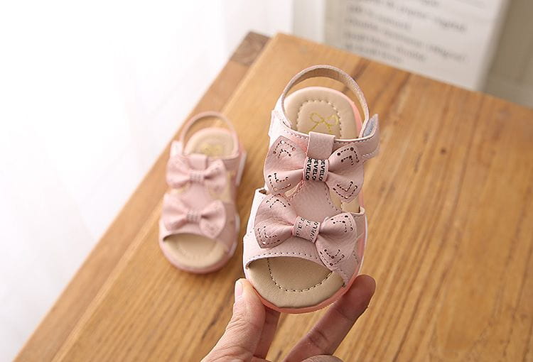 pink children’s sandals with decorative bows and subtle stitching details designed as white led flashing princess shoes perfect for cute flower flashing and flower flashing princess use.