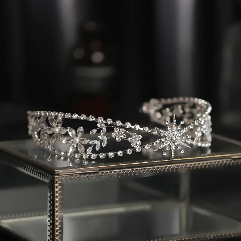 A sparkling silver bridal crown headdress adorned with intricate floral and starburst designs featuring numerous clear zircon rhinestones set in a delicate metal framework.
