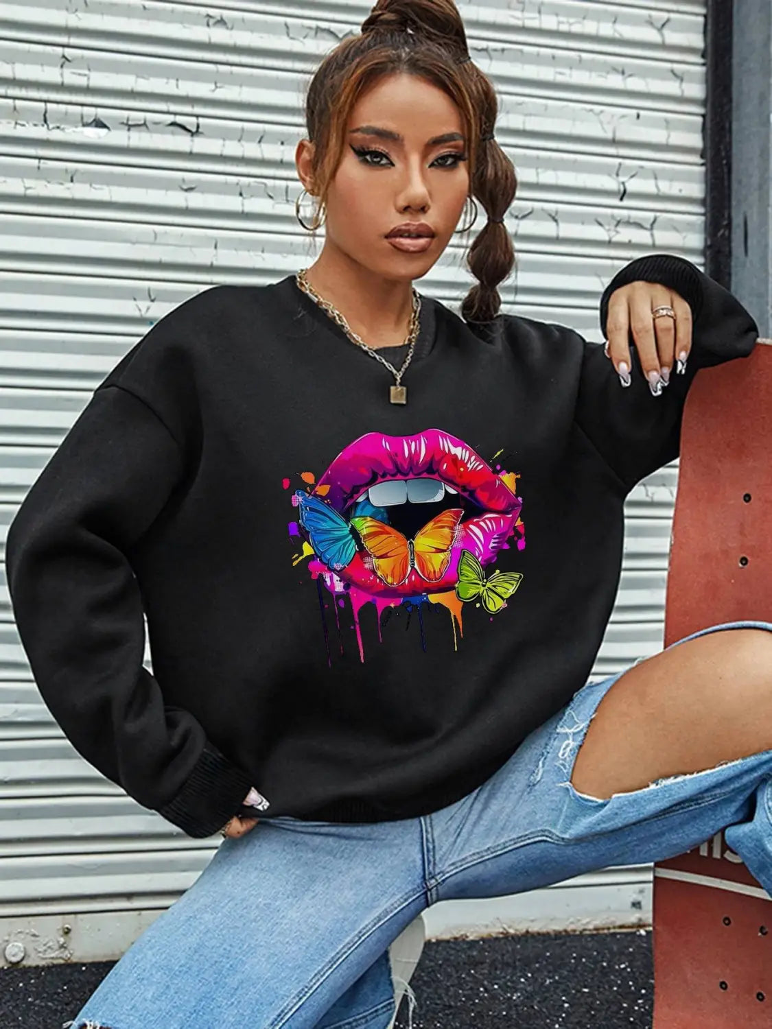 Black oversized crew neck sweatshirt featuring a vibrant dripping paint-style graphic of pink and red lips with colorful butterflies on the front.