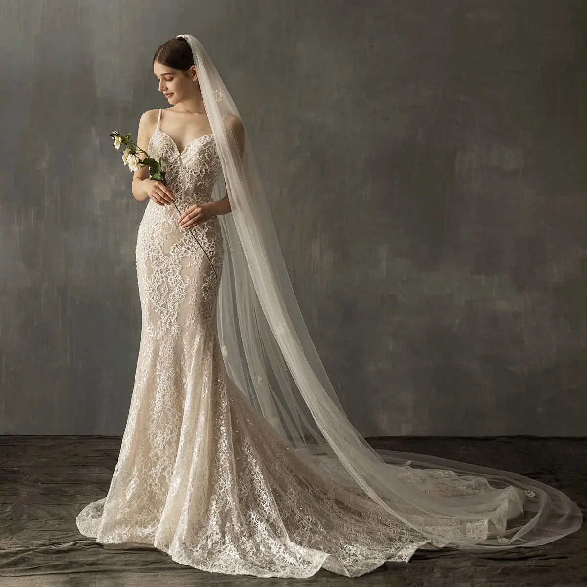 A delicate ivory lace bridal church wedding gown featuring a fitted bodice, flowing wedding pearl long train, and an attached sheer veil.