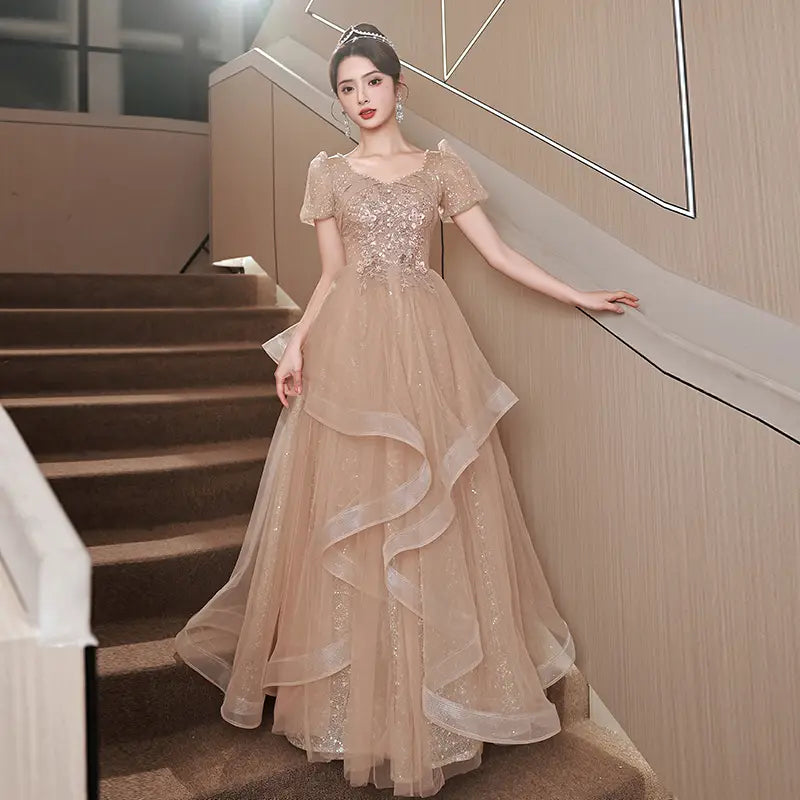 a shimmering champagne-colored blush beaded tulle luxury evening dress featuring intricate beading and a layered tulle skirt ideal for evening occasions