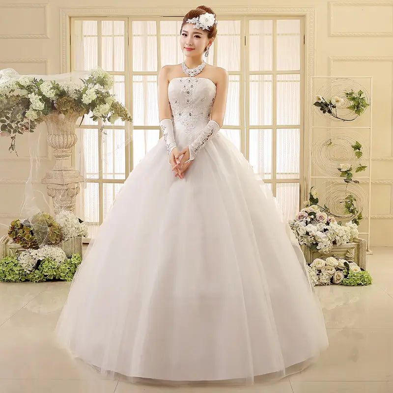 a korean style tube top lace wedding dress in white featuring intricate beading and lace detailing on the strapless bodice paired with long sheer gloves