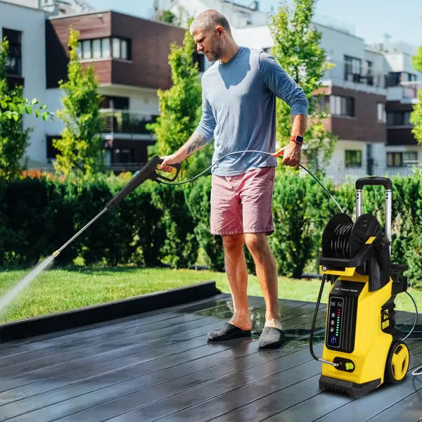 Yellow high pressure cleaning machine with hose reel featuring a portable yellow and black pressure cleaning machine with retractable hose and handle.