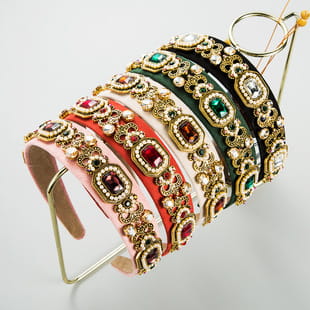 a collection of baroque colorful headbands featuring ornate gold-toned metalwork and sparkling gemstones in vibrant pink red and black colors